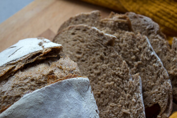 Round whole wheat bread on a table. Yellow fabric background. Top view photo of fresh baked sourdough bread. 