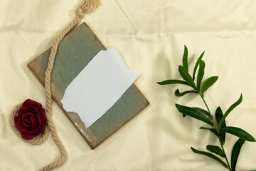 Mockup invitation, blank greeting card and flowers on bed. Flat lay, top view