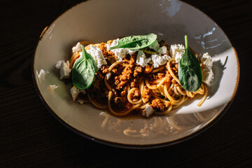 Carbonara pasta with feta cheese and basil leaves.