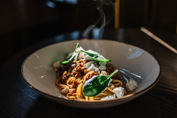 Carbonara pasta with feta cheese and basil leaves.