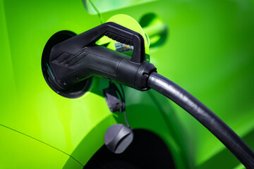 Green energy. Detail of the electric pump while charging a green car. - 426849862