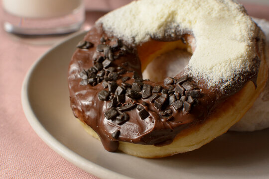 Large Donut, Dulce De Leche, Covered With Granulate Chocolate And Powdered Milk, On A Plate, In Close-up, And With A Black Background