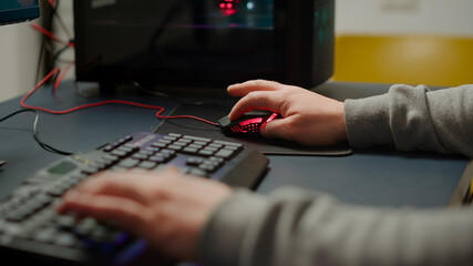 Close up hands shot of man player typing on RGB keyboard buttons while playing online shooter video game. Virtual shooter game performing in cyberspace, esports gamer esports online tournament © DC Studio