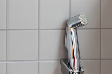 Chromium bidet shower  with grey ceramic tile in toilet. silver bidet spray shower.