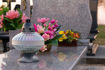 A tomb decorated with candles and flowers with cementary in the background.