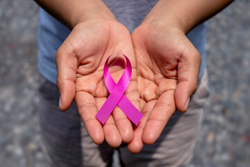 Pink ribbon on female hand, healthcare concept and breast cancer symbol.