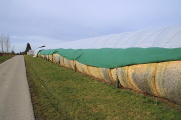 Heuballen werden mit einer Plane vor Regen geschützt