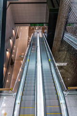 view from above of an escalator that leads down, inside a building 