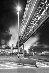 Night scene with illuminated petrochemical production plant and pipeline bridge, Antwerp, Belgium.