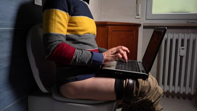 businessman sitting on the toilet wc in apartment  works on lap top computer during Covid-19 Coronavirus lockdown quarantine home - smart working concep