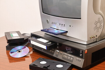 An old silver TV with built-in DVD player and a vintage VCR from the 1980s, 1990s, 2000s next to it.