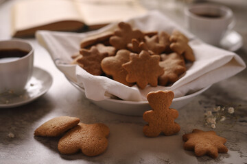 Gingerbread cookie on white dish with coffee cups and book