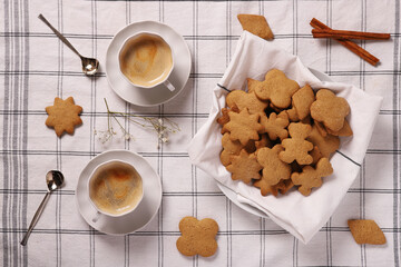 gingerbread cookies and two cups of coffee on a checkered napkin. Top view.