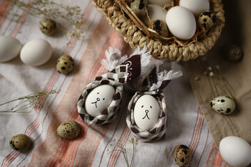 Obraz premium Two Easter eggs in the form of bunnies with a basket of eggs on a napkin. Easter concept.