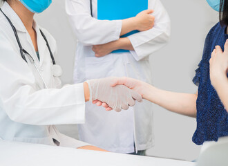 closeup hands of doctor patient shaking with trainee standing beside. white copy-space, healthcare medical care concept