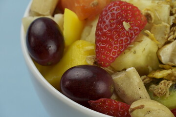Fruit salad with chestnuts and granola in a bowl. Multicolored ripe fruits. Pineapple, mango, grape, strawberry, papaya, melon, banana and kiwi..