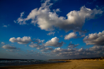 blue low sky with lots of white clouds over the seashore or ocean
