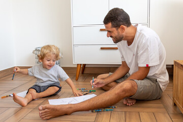 Obraz premium PAI E FILHO DESENHANDO JUNTOS NO CHÃO.