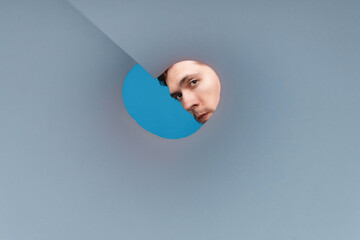 Man cool looking inside rounded tube. Close-up shot of shocked young man with round eyes
