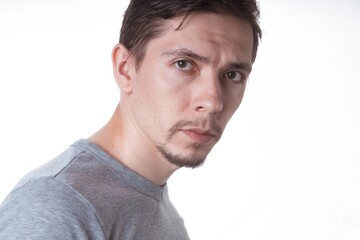 Obraz premium Portrait of a sensual young model in unlabeled gray t-shirt posing on white background. Serious man with small beard close-up portrait