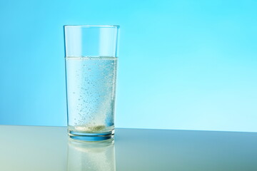 dissolving pill dissolves in water on colored background. a glass of water and an effervescent paracetamol tablet. the medicine tablet dissolves in a glass of water