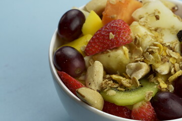 Fruit salad with chestnuts and granola in a bowl. Multicolored ripe fruits. Pineapple, mango, grape, strawberry, papaya, melon, banana and kiwi..