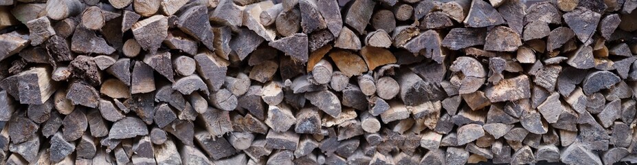 Wide view of stacked irregularly split logs for a stove, fireplace or wood stove