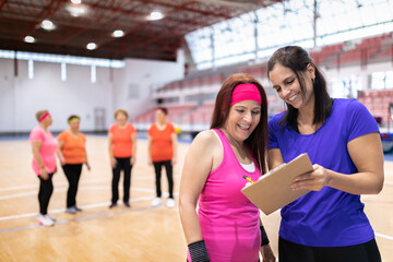 young girl sports monitor in sports center giving collective classes to older women for maintenance