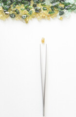 gems and tweezers on a white background..Sorting stones for jewelry.