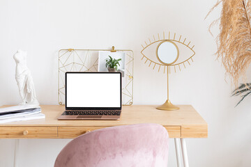 Black laptop wiith white screen on wooden table in home scandi interior. Stylish minimalistick workplace, copy space