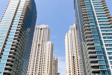 Fototapeta na wymiar Modern skyscrapers low angle symmetrical view with blue sky in the background, Dubai Marina, United Arab Emirates.