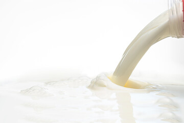 pouring milk to the surface from a plastic bottle on a white background