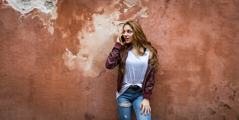 Pretty young girl talking to her smartphone with a red wall in the background