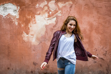 Young and happy girl turning on herself on a red wall background with copy space