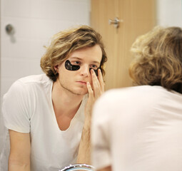 young man applying facial mask. Dark Circles.Eye patches..