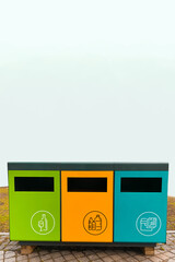 waste sorting containers. separate waste bins for glass, plastic and paper. Waste sorting, three colorful bins with symbols in the park, vertical image.
