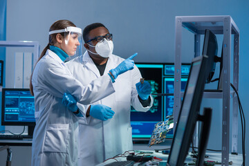 Diverse team of microelectronic engineers discuss current developments in a science lab. Workplace...