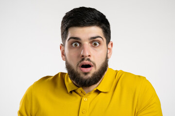 Obraz premium Frightened man afraid of something and looks into camera with big eyes full of horror over white wall background.