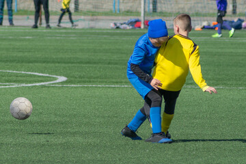Fototapeta premium Children's football. Children are playing football. The active struggle and dynamics of the boys' soccer match. The boys are recklessly fighting for the ball