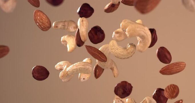 SUPER SLOW MOTION shot of cashew, hazelnut and almond nuts pile flying against bright background. Shot with high speed video camera, 720 FPS