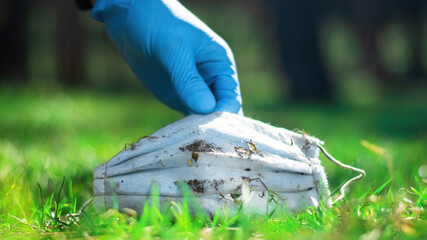 Man picking up dirty medical masks from the ground