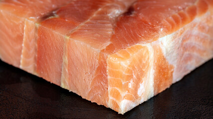 Cube piece of raw pink salmon fish on black background