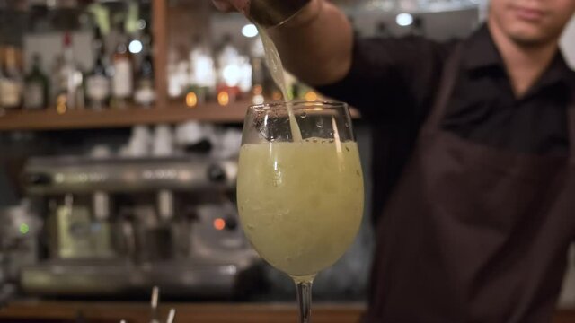 Bartender Pouring Tropical Mai Tai Cocktail Into a Wine Glass with Crushed Ice