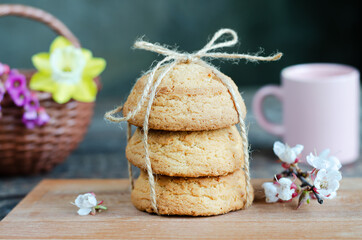 Oatmeal cookies on a wooden board, flowers and a mug. Selective focus