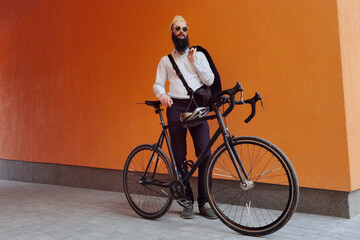 A young stylish hipster posing next to his bicycle.