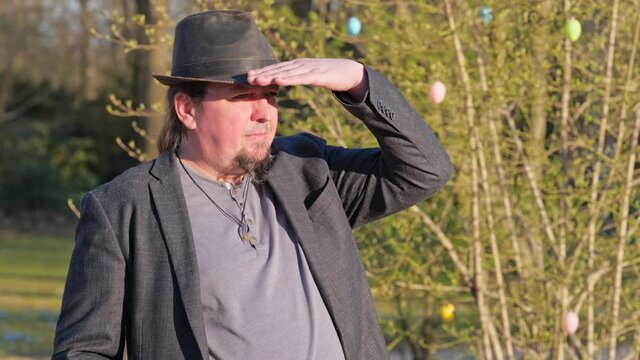 [4k] middle aged man wearing a hat is shielding his eyes with his hand from sunlight