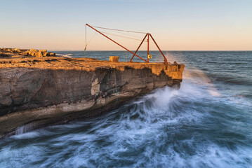 Calm sunset landscape image of Portland in Weymouth, Dorset with long exposure wave formations and peaceful setting sun