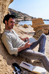 A young writer works with his laptop from the beach