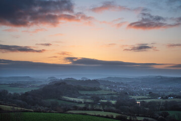 Fototapeta premium Beautiful vibrant sunrise landscape image of misty view towards Symondsbury village in Dorset on a Spring morning