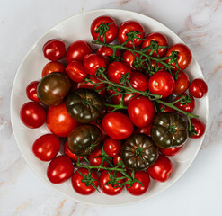Different kind of ripe organic tomatoes on white marble background.Top view.